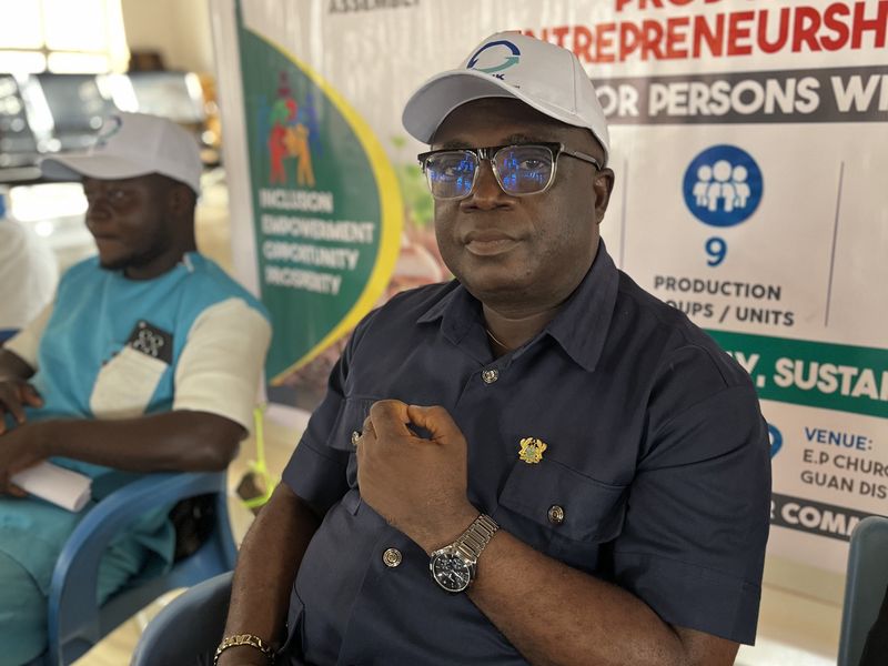 An official seated in front of the programme banner addressing the gathering